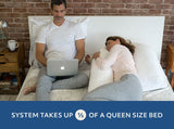 A man working on a laptop in bed next to a woman who is sleeping with the MedCline Shoulder Relief System.