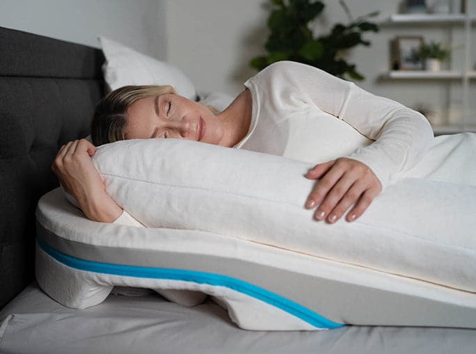 A woman sleeping on the MedCline Shoulder Relief System