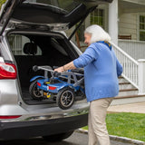 An older woman placing a folded Journey So Lite Scooter into an open car trunk.