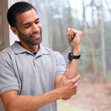 A man holding his arm with a black EMbr Wave 2 wristband